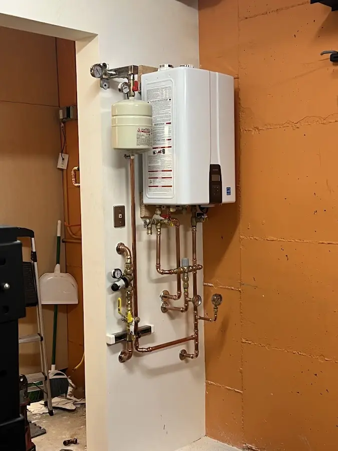 Plumbing technician inspecting water heater connections in Fort Carson
